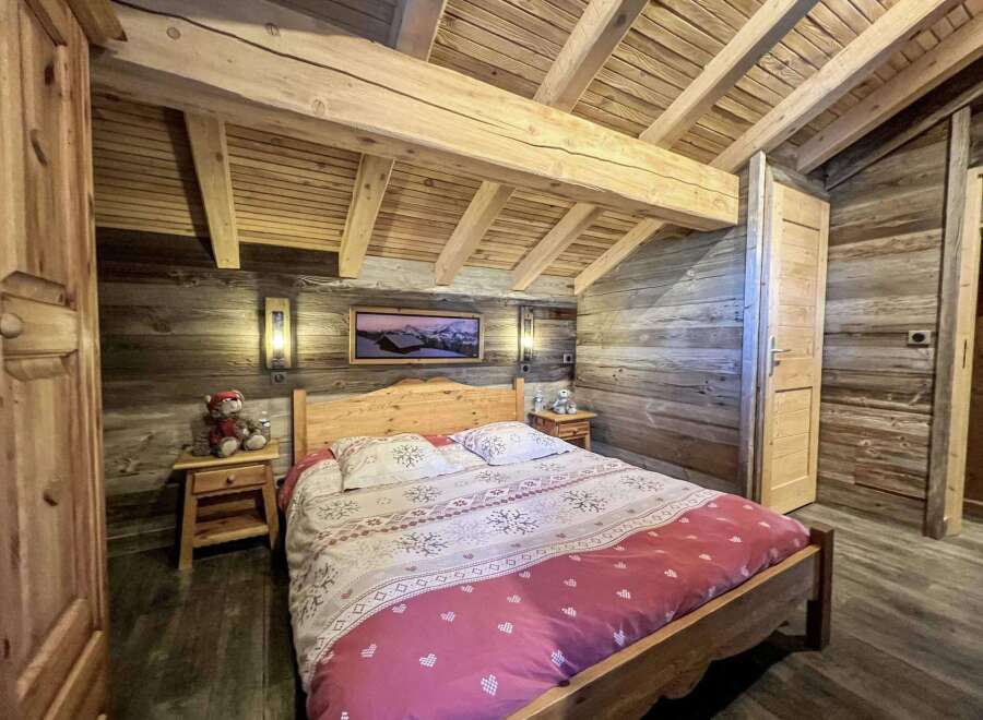 Cozy chalet bedroom with wooden beams, rustic walls, and a comfortable double bed.