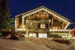 Luxury chalet nestled in the snowy mountains, featuring stunning nighttime views and charming exterior lighting.