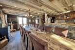 This stunning chalet boasts a magnificent reclaimed wood dining table perfect for large gatherings, surrounded by comfortable leather chairs.