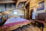 Cozy chalet bedroom with wooden walls and beams, featuring a comfortable double bed and plush bathrobes.