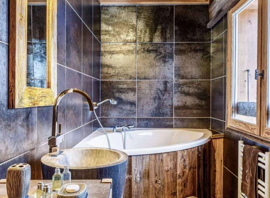 Rustic bathroom with wooden beams, stone sink, and a freestanding bathtub.