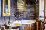 Rustic bathroom with wooden beams, stone sink, and a freestanding bathtub.