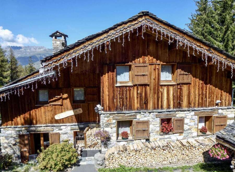 This charming chalet boasts a rustic wooden exterior with stone accents, creating a cozy and inviting atmosphere.