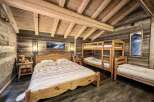 Cozy chalet bedroom with wooden beams, rustic decor, and a double bed.