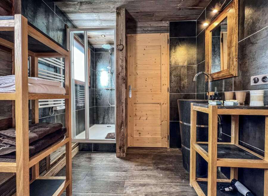 This luxurious bathroom boasts a spacious shower, sleek dark tile, and rich wood accents throughout.