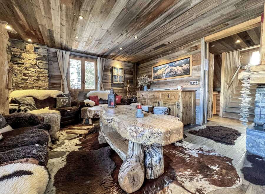 Rustic mountain chalet with wood-paneled walls and ceilings, featuring a large, live-edge coffee table and comfortable seating areas.