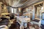 Rustic mountain chalet with wood-paneled walls and ceilings, featuring a large, live-edge coffee table and comfortable seating areas.