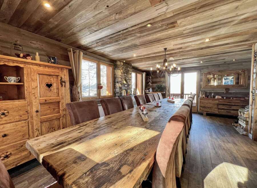 This stunning chalet boasts a magnificent, rustic dining table perfect for large gatherings, surrounded by comfortable seating.