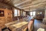 This stunning chalet boasts a magnificent, rustic dining table perfect for large gatherings, surrounded by comfortable seating.