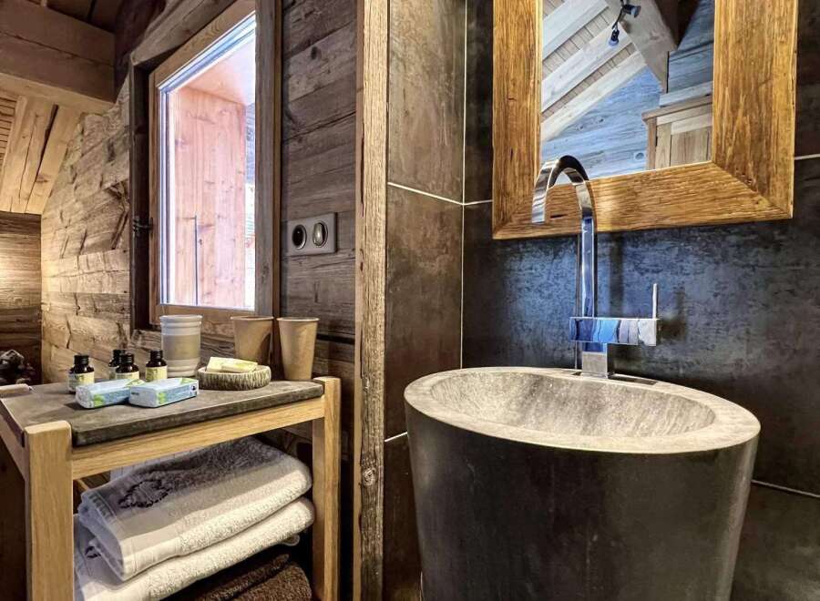 Rustic-chic bathroom with a unique stone sink and wooden shelving.