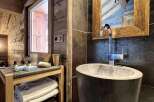 Rustic-chic bathroom with a unique stone sink and wooden shelving.