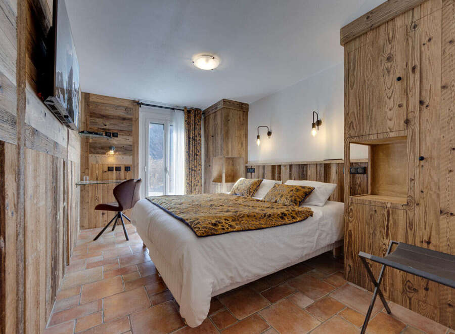 This cozy bedroom features rustic wooden paneling and a comfortable bed with a patterned throw.