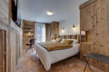 This cozy bedroom features rustic wooden paneling and a comfortable bed with a patterned throw.