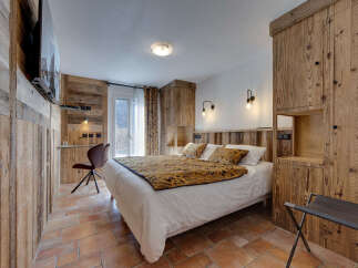 This cozy bedroom features rustic wooden paneling and a comfortable bed with a patterned throw.