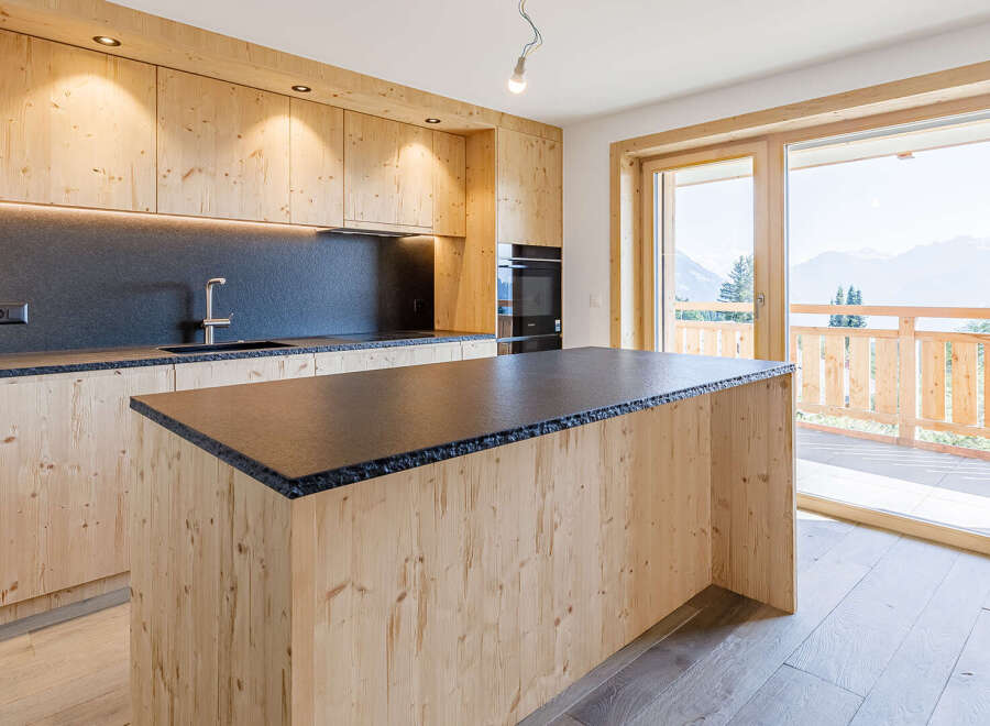 This stunning kitchen boasts a modern design with natural wood cabinetry and a sleek black countertop.