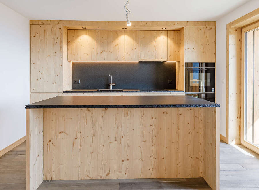 This stunning kitchen boasts a modern design with natural wood cabinetry and a sleek black countertop.