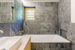 Discover a modern bathroom retreat featuring sleek gray tile and a luxurious soaking tub.