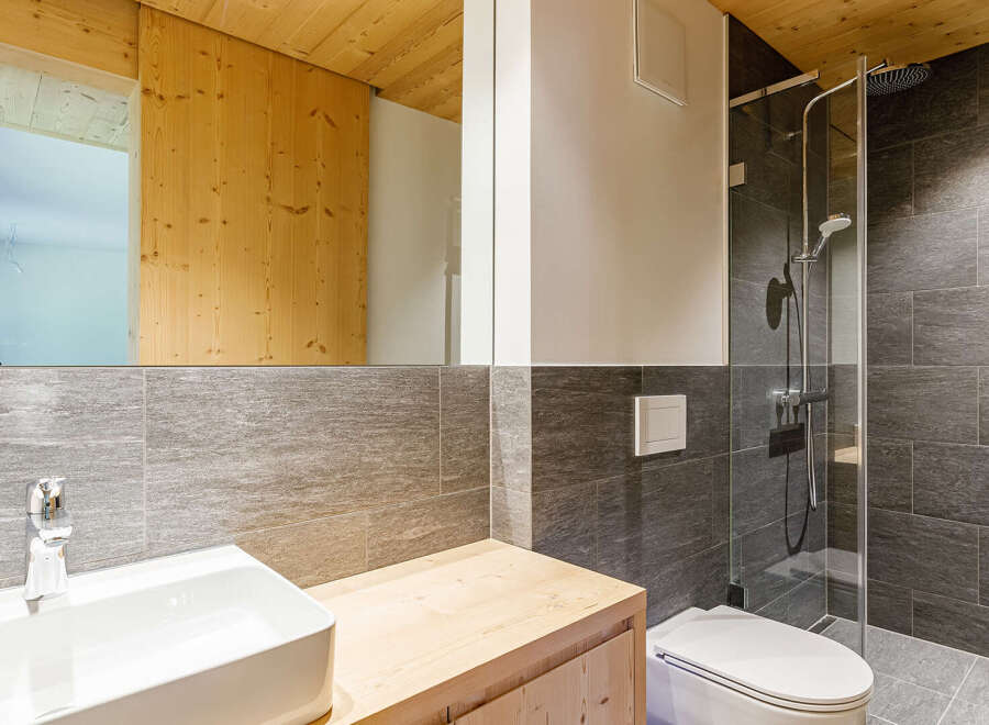 This modern bathroom features a sleek design with a wooden vanity and a stylish sink.