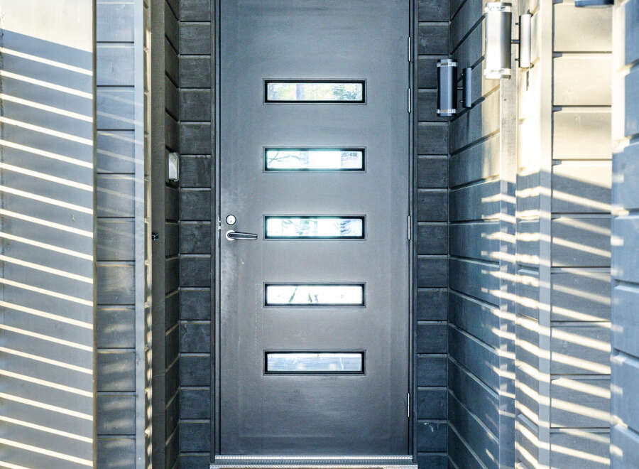 Modern home entrance featuring a sleek, dark gray door with rectangular windows.