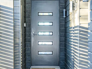 Modern home entrance featuring a sleek, dark gray door with rectangular windows.