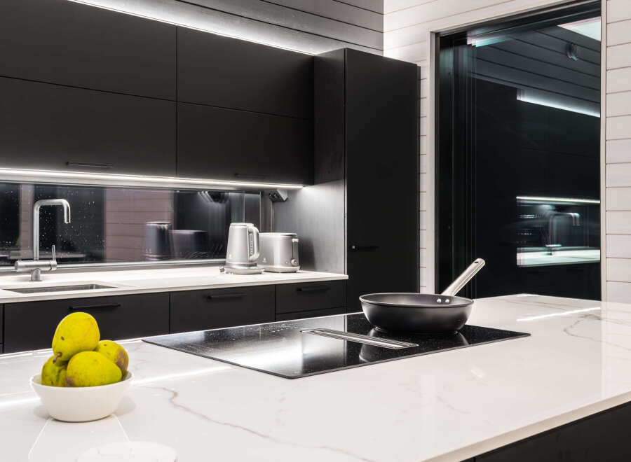 Modern kitchen design with sleek black cabinetry and a contrasting white countertop.