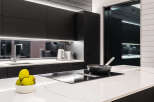 Modern kitchen design with sleek black cabinetry and a contrasting white countertop.