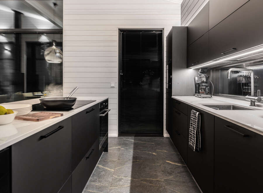 This modern kitchen boasts sleek black cabinetry and a pristine white countertop, creating a sophisticated and stylish space.