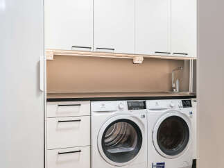 This modern laundry room features sleek white cabinetry and appliances, creating a clean and functional space.