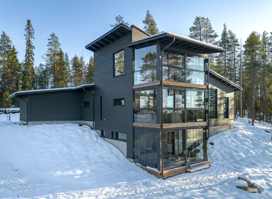 This modern home boasts a striking design with its dark gray exterior and expansive glass windows.