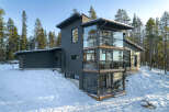 This modern home boasts a striking design with its dark gray exterior and expansive glass windows.