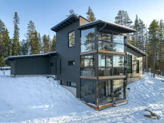This modern home boasts a striking design with its dark gray exterior and expansive glass windows.