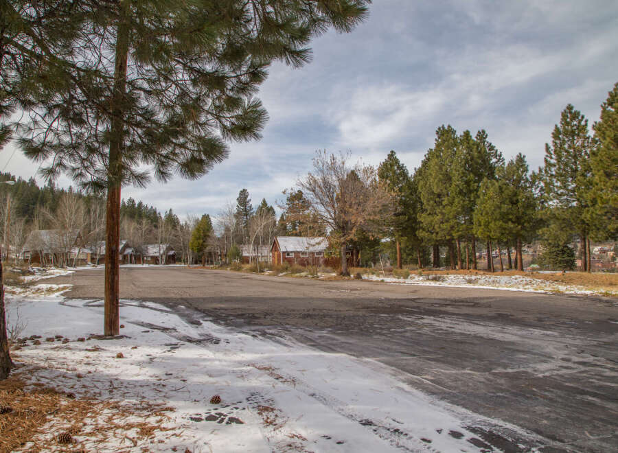 This secluded winter wonderland features rustic cabins nestled amongst towering pine trees, offering a tranquil escape.