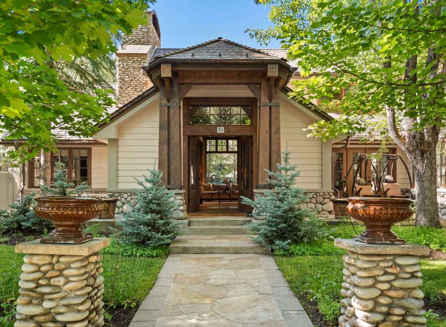This stunning home boasts a charming stone and wood exterior, complemented by lush landscaping and meticulously placed stonework.
