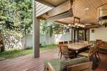 This stunning outdoor patio boasts a large wooden dining table, surrounded by comfortable wooden chairs with striped cushions, perfect for al fresco dining.
