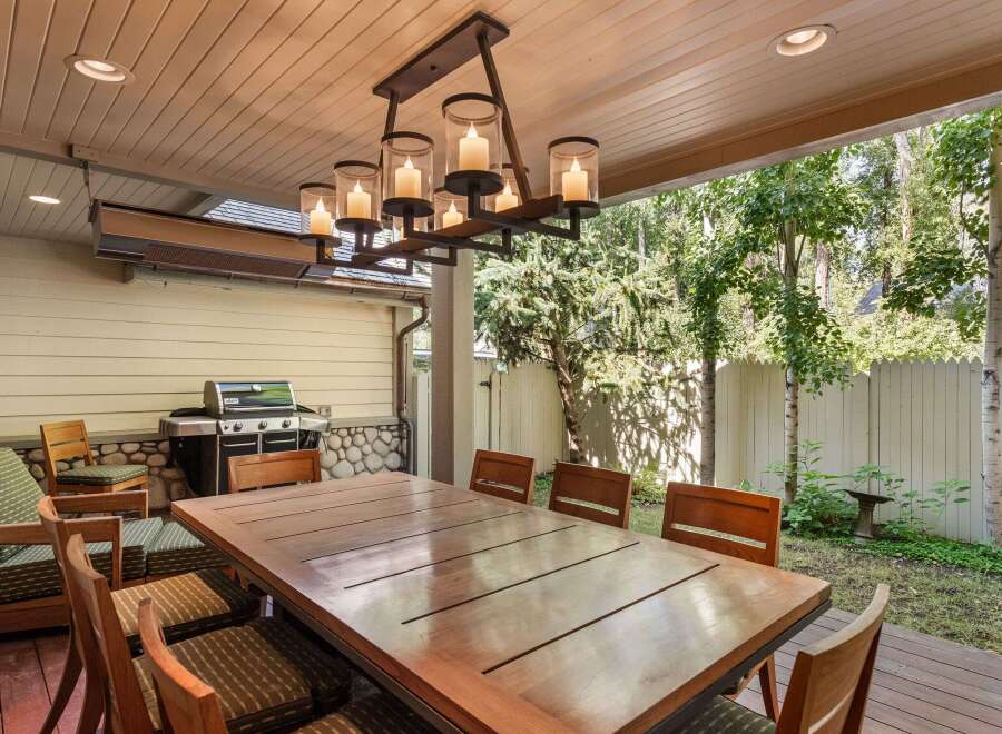 This outdoor patio features a large wooden dining table with seating for eight, perfect for enjoying meals al fresco.