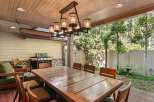 This outdoor patio features a large wooden dining table with seating for eight, perfect for enjoying meals al fresco.