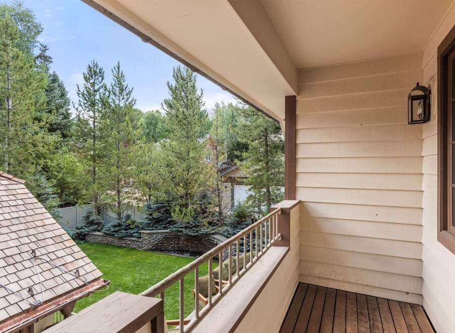 This charming balcony boasts a picturesque view of a lush green lawn and mature trees, creating a serene and private outdoor space.