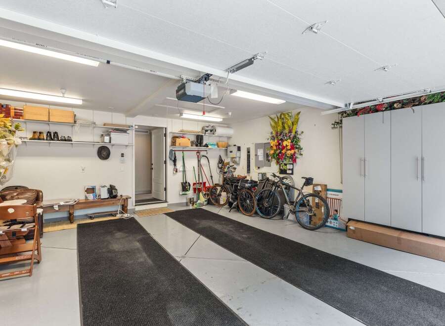 This spacious garage boasts ample storage solutions, including overhead shelving, wall cabinets, and floor-to-ceiling storage units.
