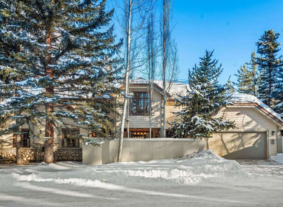 This stunning winter home boasts a charming exterior with a large attached garage and a fenced yard.