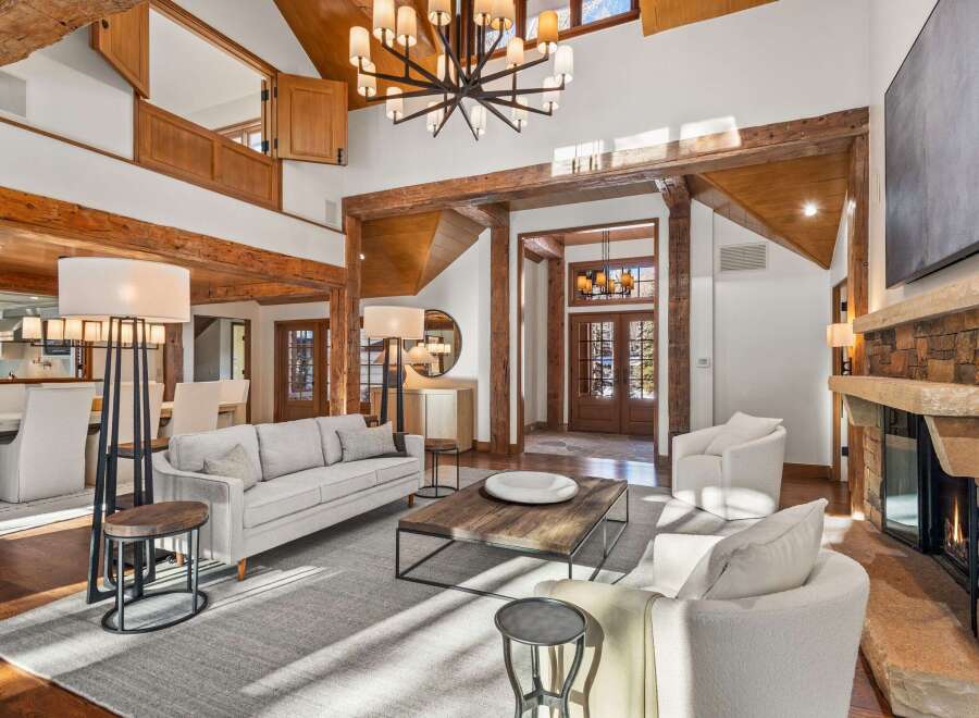This stunning living room boasts a double-height ceiling with exposed wooden beams, creating an open and airy atmosphere.