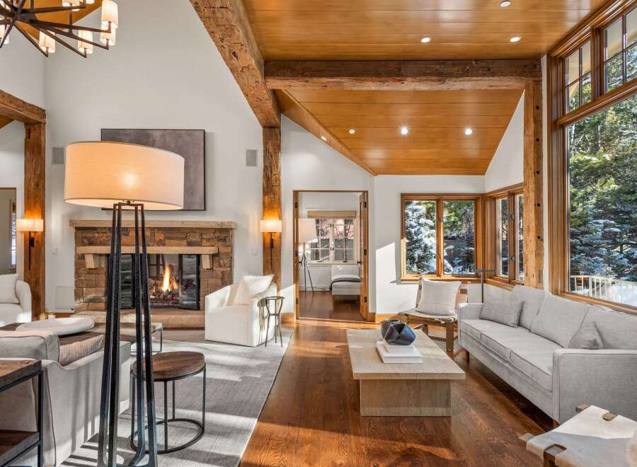 This stunning living room boasts a cozy fireplace, large windows offering breathtaking views, and hardwood floors.