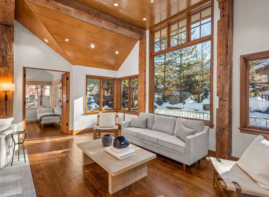 This stunning property boasts a spacious living area with hardwood floors, a cozy sofa, and large windows offering breathtaking views of the snowy landscape.