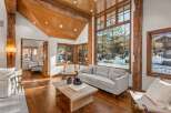 This stunning property boasts a spacious living area with hardwood floors, a cozy sofa, and large windows offering breathtaking views of the snowy landscape.
