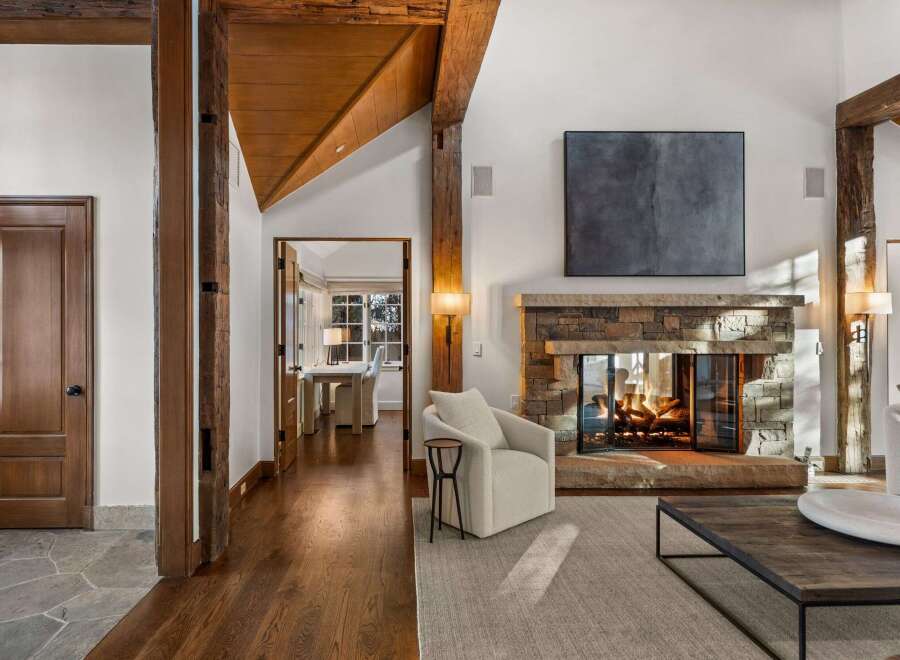 This stunning living room boasts a cozy fireplace, hardwood floors, and exposed wooden beams, creating a warm and inviting atmosphere.