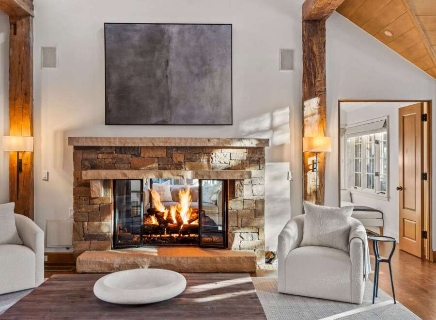 This stunning living room boasts a rustic-chic fireplace as its centerpiece, surrounded by plush seating and bathed in natural light.