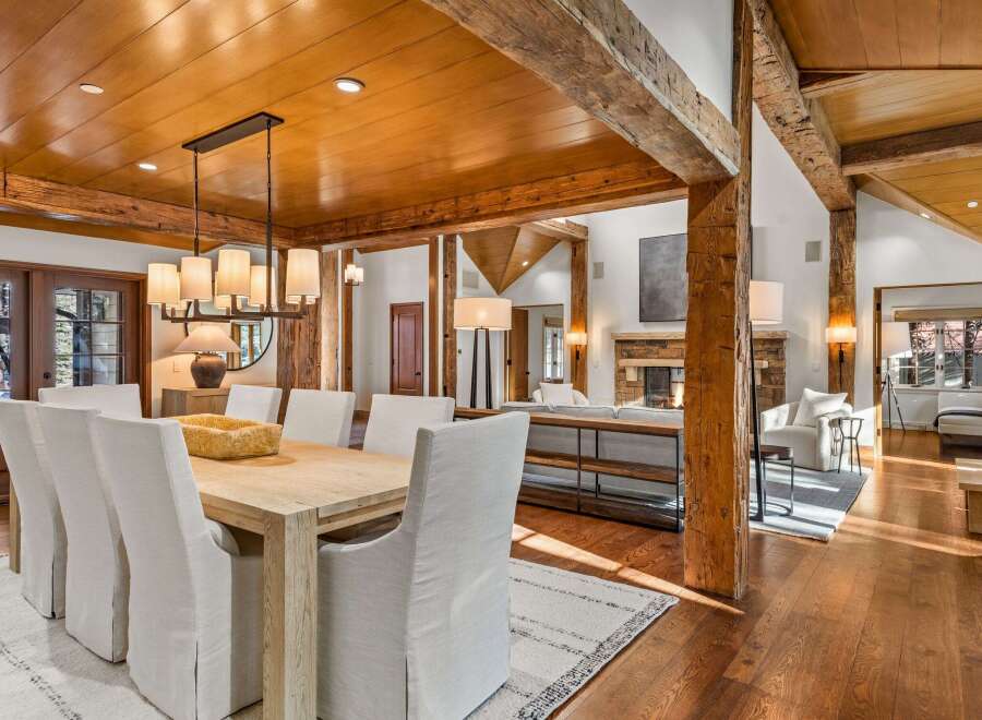 This stunning home boasts a spacious dining area with a large wooden table and comfortable white chairs, perfect for family gatherings.
