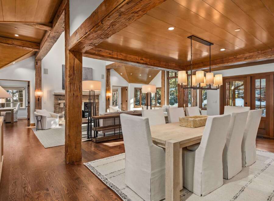 This stunning home boasts a spacious open floor plan with exposed wooden beams, hardwood floors, and large windows offering abundant natural light.