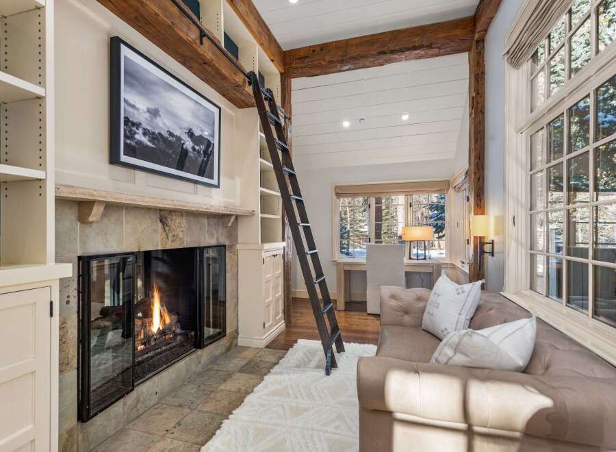 Cozy mountain retreat with a stunning stone fireplace, built-in bookshelves, and a charming window seat.