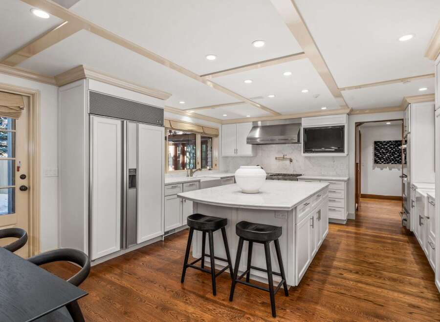 This stunning kitchen boasts a spacious island with seating, sleek white cabinetry, and high-end stainless steel appliances.