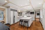 This stunning kitchen boasts a spacious island with seating, sleek white cabinetry, and high-end stainless steel appliances.